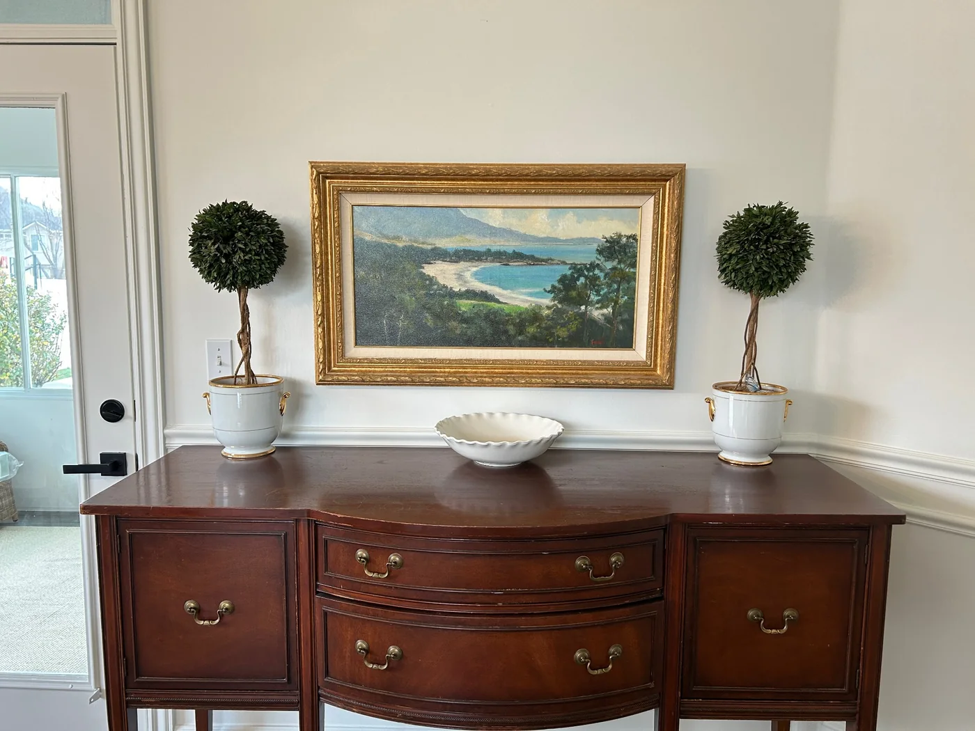 Gold framed landscape installed above a sideboard