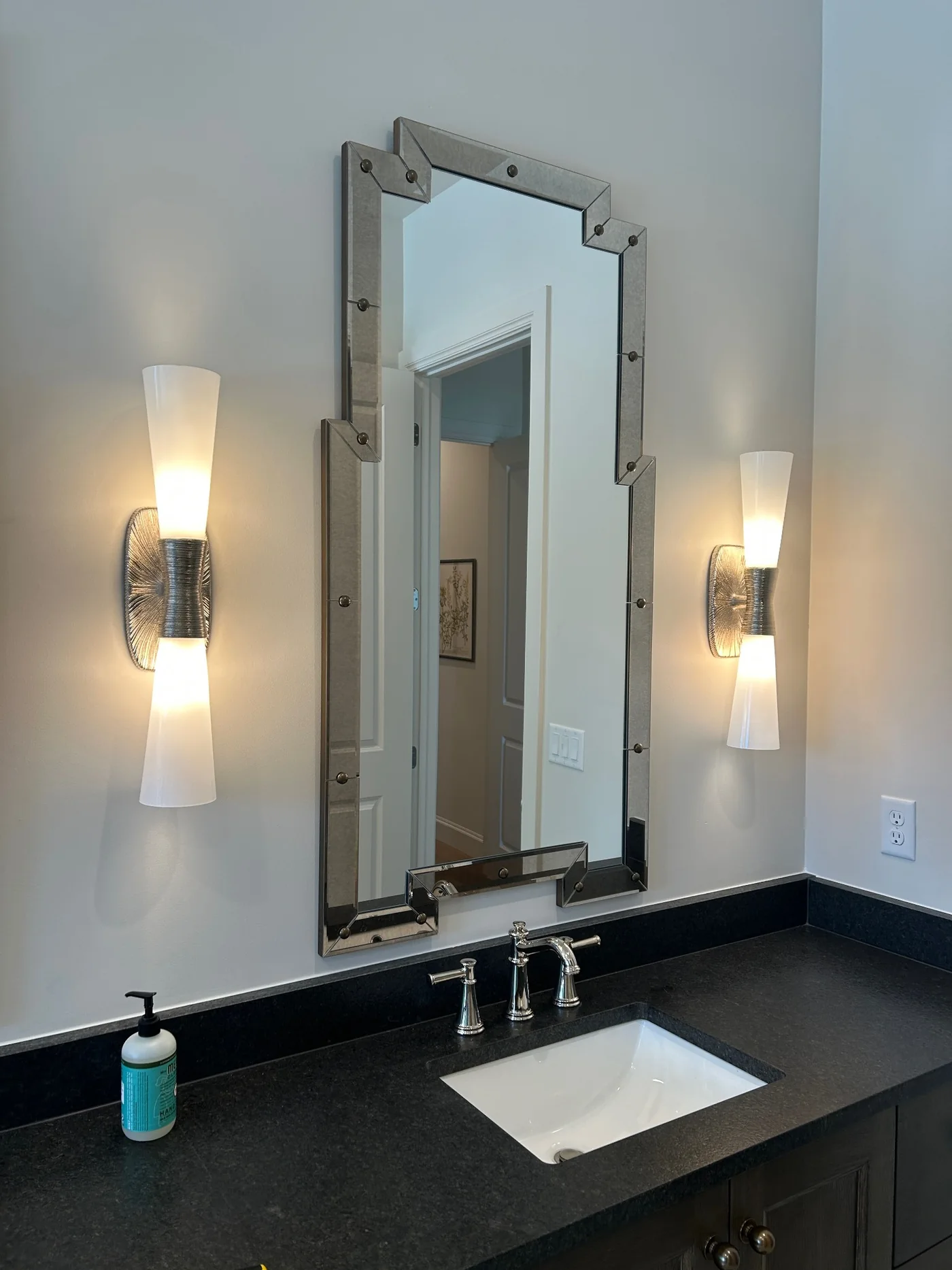 Tall decorative mirror installed between bathroom sconces